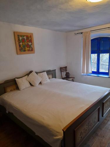 a bedroom with a large white bed with a window at Casa Anca Cheile Nerei in Socolari