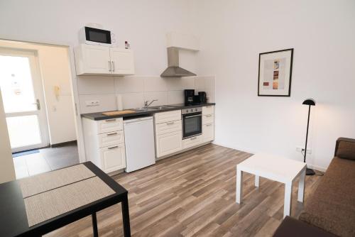 a kitchen with white cabinets and a table in a room at FeWo Engler Lüneburg Wallstraße in Lüneburg