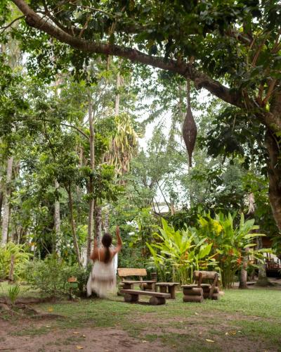 a woman standing under a tree in a park at Solar Pitanga - Taipu de Fora in Barra Grande