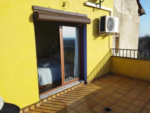 ein gelbes Haus mit einem Bett und einem Fenster in der Unterkunft Casa el Sereno in Salas Bajas
