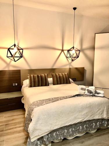 a bedroom with a large bed with two lights at EL AGAVE DE MERESE APARTAMENTO in Las Toscas