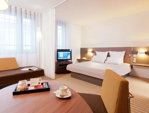 a hotel room with a bed and a tv at Novotel Suites Lille Europe in Lille