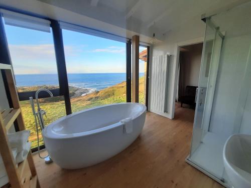 baño con bañera blanca grande y ventana grande en Posada Punta Liñera, en San Vicente de la Barquera