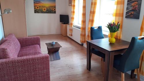 ein Wohnzimmer mit einem Tisch, einem Sofa und einem Stuhl in der Unterkunft 1-Zimmer-Apartment 2 Hochparterre in Lübeck