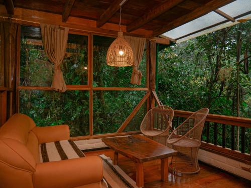 a screened in porch with a couch and a table at Casa de Vista Alta in Mindo