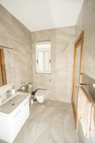 a bathroom with a white sink and a toilet at Bugibba Deluxe Penthouse with terrace & communal swimming pool in St. Paul's Bay