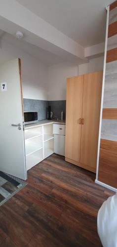 an empty kitchen with white cabinets and wooden floors at En suite single bedroom, close to city centre in Sheffield