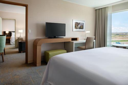 a hotel room with a bed and a desk with a television at The Westin Denver International Airport in Denver