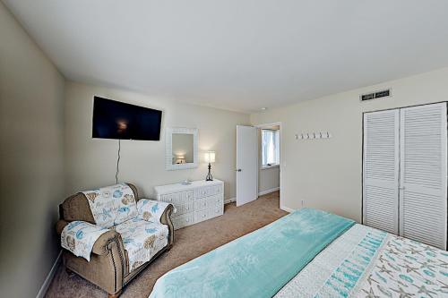 a bedroom with a bed and a chair and a tv at Hilton Head Cabanas 29 in Hilton Head Island