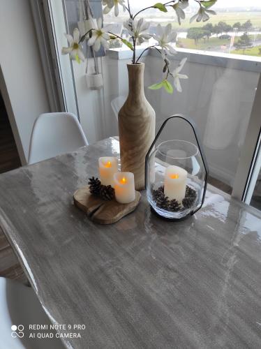 a table with candles and a vase on it at Appartement de charme in Courseulles-sur-Mer