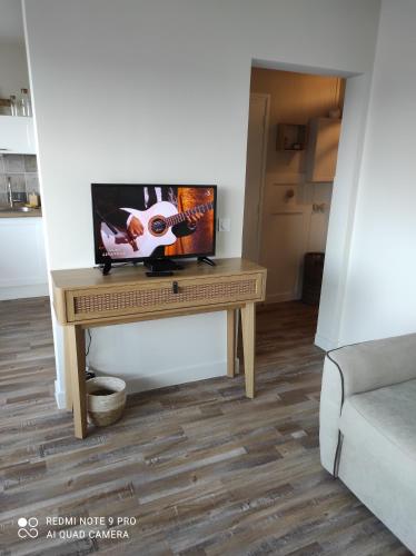 - une télévision assise sur une table dans le salon dans l'établissement Appartement de charme, à Courseulles-sur-Mer