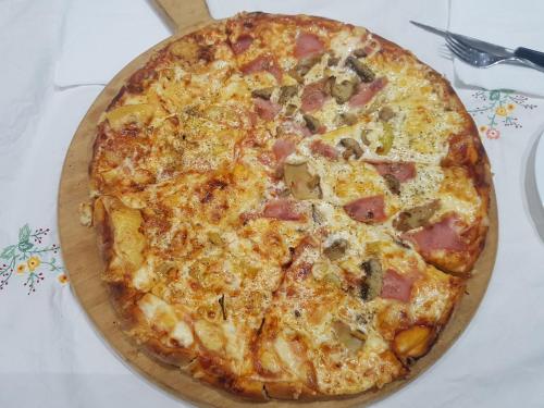 a pizza with ham and cheese on a table at Krystal Hotel in Krystallopigí