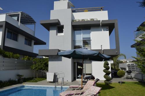 a house with a swimming pool and an umbrella at Fleur De Mer Villa in Hi-Tech Style in Limassol