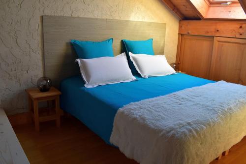 - un lit bleu avec des oreillers blancs dans l'établissement Autour du Soleil, à Chindrieux