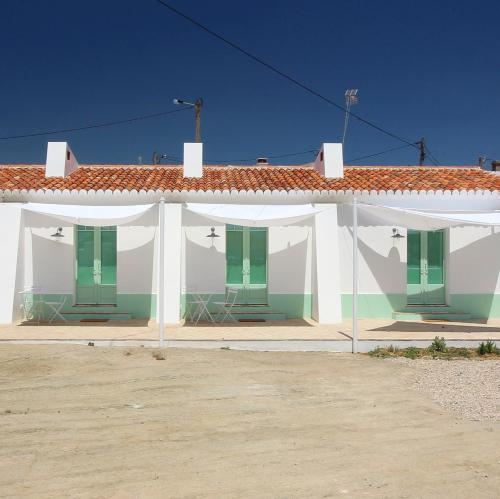 a white building with green shutters on it at Herdade de Alagães in Mértola