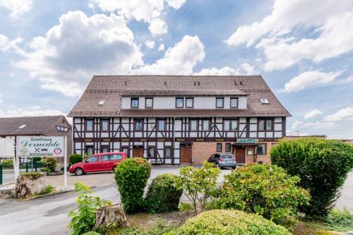 ein großes Gebäude mit Autos auf einem Parkplatz in der Unterkunft Gasthaus Dernedde in Osterode