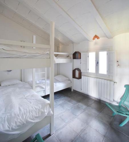 a bedroom with two bunk beds and a green chair at LosGuachos_ casa rural in Villalgordo del Jucar