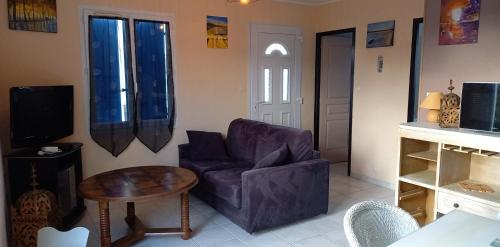 una sala de estar con un sofá y una mesa en En plein cœur de l’Île d'Oléron, suite parentale., en Dolus d'Oléron