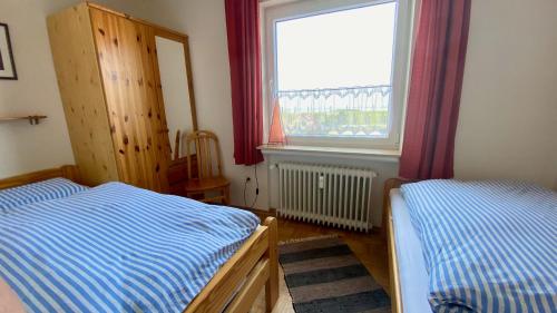 1 dormitorio con 2 camas y ventana en Apartment CAPTAIN'S LODGE, en Norddeich