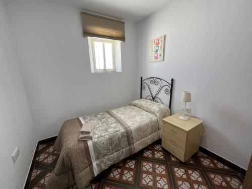 ein Schlafzimmer mit einem Bett und einem Tisch und einem Fenster in der Unterkunft Alojamiento Los Alcornocales in Medina-Sidonia