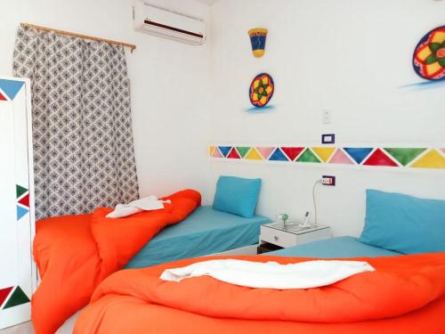 two beds in a room with orange and blue at Lawanda Nubian House in Aswan