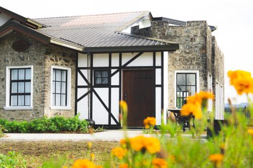 a stone house with a brown door and some flowers at Dover Cottage in Nuwara Eliya