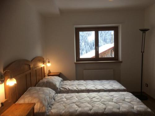 1 dormitorio con 2 camas y ventana en Pelmo Mountain Lodge, en Selva di Cadore
