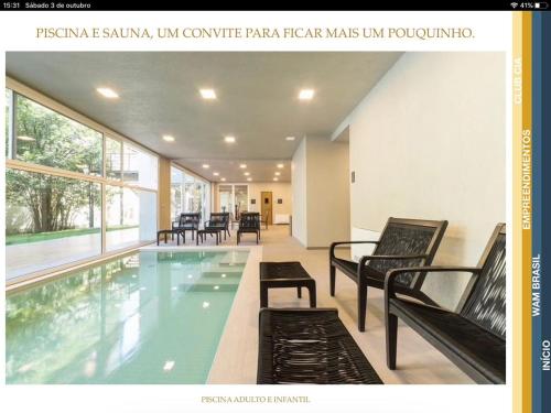 a swimming pool with benches and chairs in a building at Laghetto Stilo Borges in Gramado