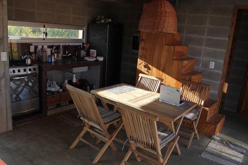 cocina con mesa de madera con sillas y ordenador portátil en Casa Xanelas, casa de playa en Punta Rubia, Rocha, en La Pedrera