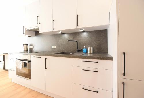 a white kitchen with white cabinets and a sink at myQuartier Central City Suites in Innsbruck