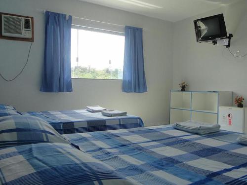 1 dormitorio con 2 camas y ventana con TV en Hotel Pousada Positiva, en Itabuna