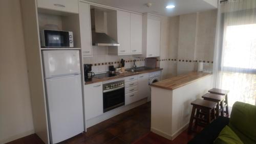 eine Küche mit weißen Schränken und einem weißen Kühlschrank in der Unterkunft Las Margas. Golf. Bici. Esquí. Piscina. in Sabiñánigo