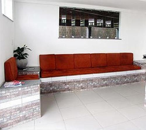 a red couch sitting under a window in a room at Hotel Pousada Positiva in Itabuna