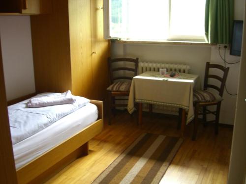 a small room with a table and a bed and a table and chairs at Hotel Villa Emilia in Ortisei
