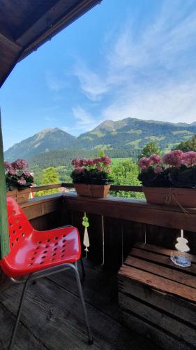 a red chair sitting on top of a balcony with flowers at Adlerhorst - Apartment im Niedersimmental in Oey