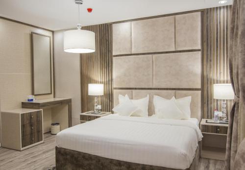 a bedroom with a large white bed and a mirror at Veliton Hotel in Al Khobar