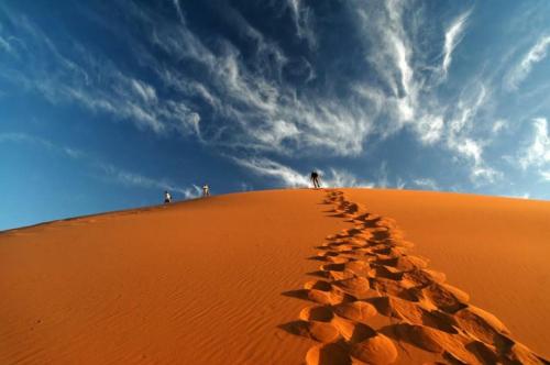 a group of people standing on top of a sand dune at Desert Romantic Camp in Merzouga
