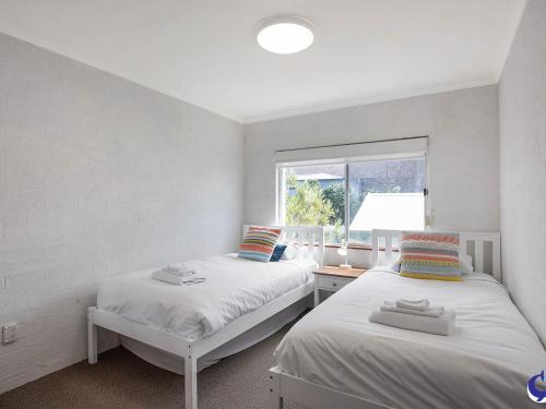 two beds in a room with a window at Sapphire Waters Unit 3 in Narooma