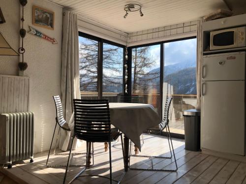une cuisine avec une table et des chaises ainsi qu'une grande fenêtre dans l'établissement Grand studio La Foux d Allos avec vue et terrasse, à La Foux d'Allos