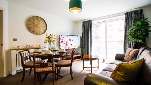 a living room with a table and a clock on the wall at High Street - 2BD Apt - King Beds - Parking - Wise Stays in Southampton