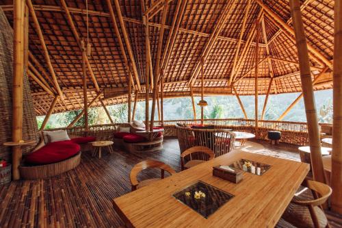 een restaurant met een tafel en stoelen en een groot dak bij Temple House 3bds Eco Bamboo House Pool River View in Bringkit