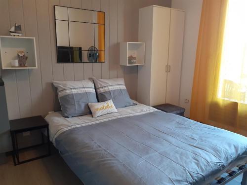 une chambre avec un lit avec des draps bleus et un miroir dans l'établissement Appartement Canet Sud Jardin et parking, à Canet