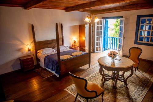 Un dormitorio con una cama y una mesa y sillas. en Casarão Milho Verde, en Milho Verde