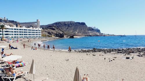 una playa con gente en la arena y el océano en Sweet Sunset Playa del Cura en Mogán