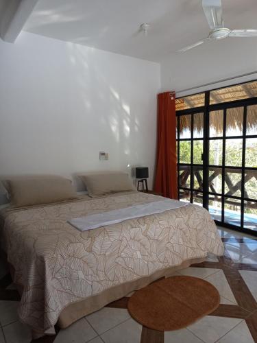 um quarto com uma cama e uma grande janela em Villa del Mar em Zipolite