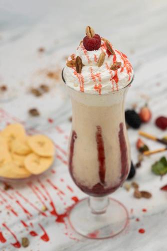 a milkshake with whipped cream and nuts on a table at Veliton Hotel in Al Khobar