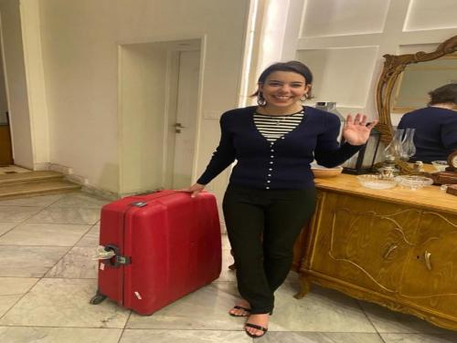 een vrouw die naast een rode koffer staat bij Paris Hotel Cairo in Caïro