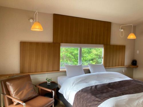 um quarto com uma cama, uma cadeira e uma janela em Villa Del Mar Nosoko em Ishigaki