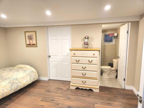 ein Schlafzimmer mit einem Bett und einer Kommode sowie ein Badezimmer in der Unterkunft Cozy spacious Apt In Laval, Greater Montreal in Laval