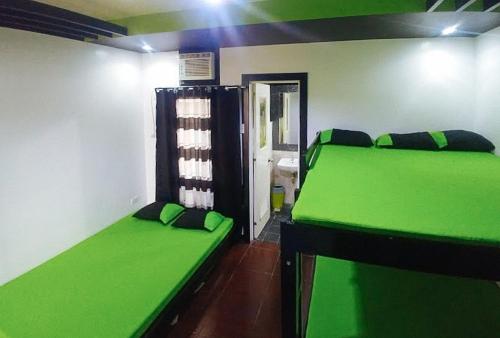 Zimmer mit 2 grünen Betten und einem Spiegel in der Unterkunft Casa Demetria Duplex Hot Spring Resort Laguna in Pansol